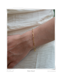 Colocho Bracelet, close-up worn on a model's wrist over a white top, a solid 18k gold twisted chain bracelet. Tarnish-resistant and made for everyday wear — Maya & Mason handcrafted fine jewellery.