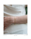 Aspen Bracelet worn on a model's wrist over a white top, a solid 18k gold pebble-link chain bracelet. Tarnish-resistant and made for everyday wear — Maya & Mason handcrafted fine jewellery.