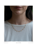 Mini Curl Necklace, worn on a model's neck over a light gray top, a solid 18k gold layered necklace with small curl and teardrop charms. Tarnish-resistant and made for everyday wear — Maya & Mason handcrafted fine jewellery.