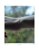 Curl Bracelet worn on a model's wrist outdoors against a blurred natural background, a solid 18k yellow gold chain bracelet featuring eight signature curl charms. Tarnish-resistant and made for everyday wear — Maya & Mason handcrafted fine jewellery.