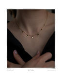 Curl Necklace, model wearing a delicate chain necklace featuring seven gently formed gold curls, worn close to the collarbone, solid 18k yellow gold. Tarnish-resistant and made for everyday wear — Maya & Mason handcrafted fine jewellery.